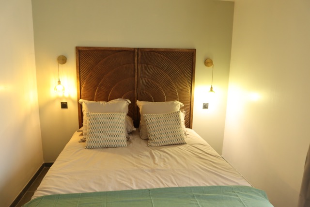 Chambre avec lit double et tête de lit en bois sculpté du Gîte L'Écume